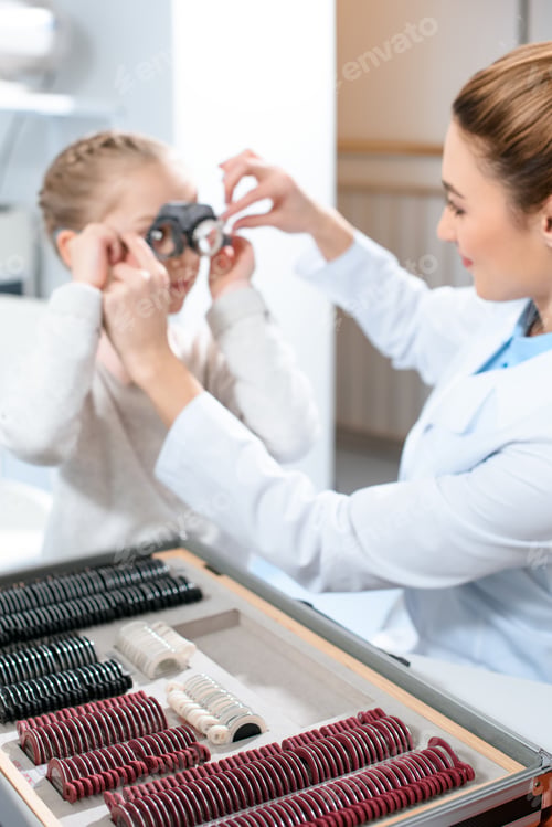 Preview: oculist examining kid eyes with trial frame and lenses