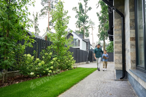 Preview: Male and his son are walking through yard of country house