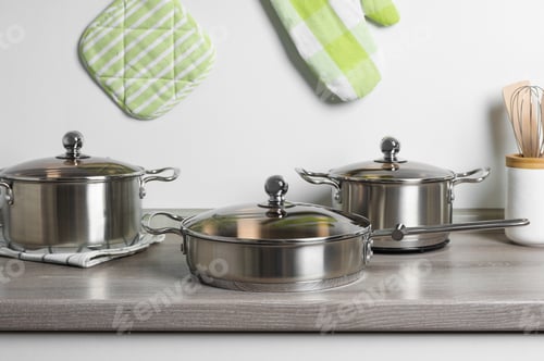 Preview: New cookware set on wooden countertop near light wall