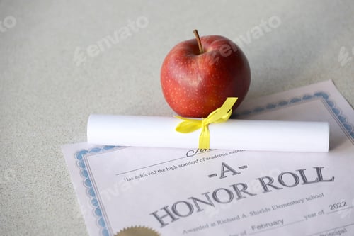 Preview: A honor roll lies on table with small scroll and red apple. Education documents
