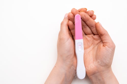 Preview: Positive pregnancy test in woman hands on the white background