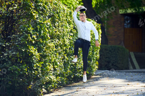Preview: Happy young man jumping around at a hedge