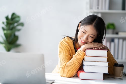 Preview: Asian college student relaxing after reading and doing homework for the project while sitting in a c