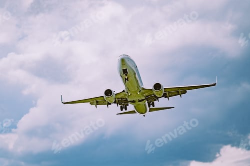 Preview: Low angle shot of an airplane flying against a cloudy blue sky
