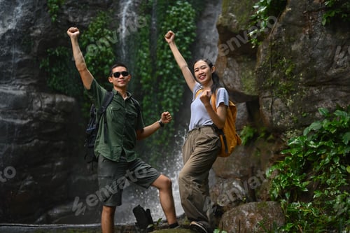 Preview: Young couple tourist raising hand to celebrating achievement, success and goal in forest