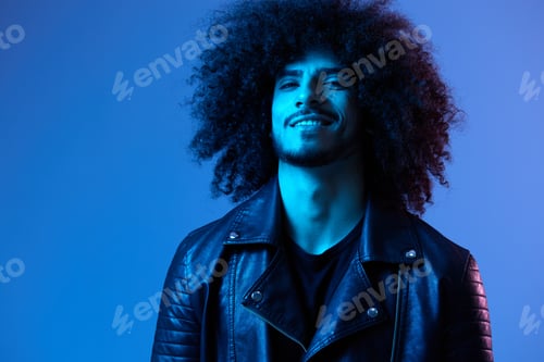 Preview: Portrait of fashion man with curly hair on blue background multinational, colored light, black