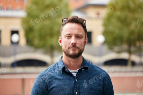 Preview: Man with a beard standing outdoors in a city on a quiet street