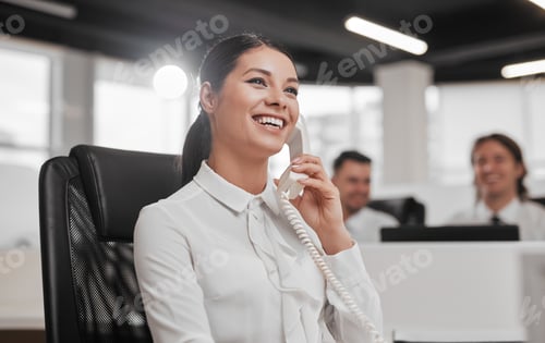 Preview: Smiling female help desk employee talking on telephone in office