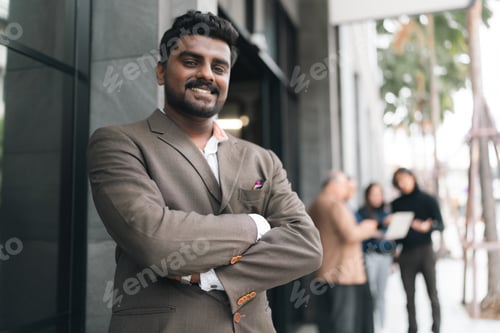 Preview: Smiling businessman in suit outside office building