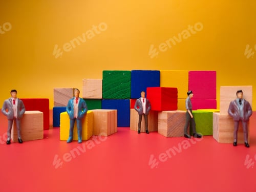 Preview: Closeup of miniature businessmen and colorful wooden cubes on a yellow background - Business concept