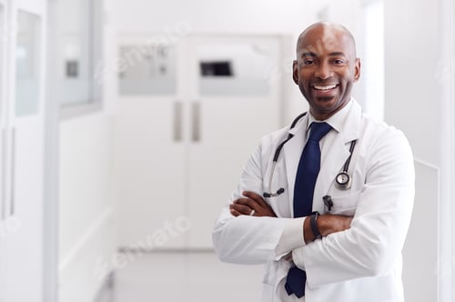 Preview: Portrait Of Mature Male Doctor Wearing White Coat Standing In Hospital Corridor