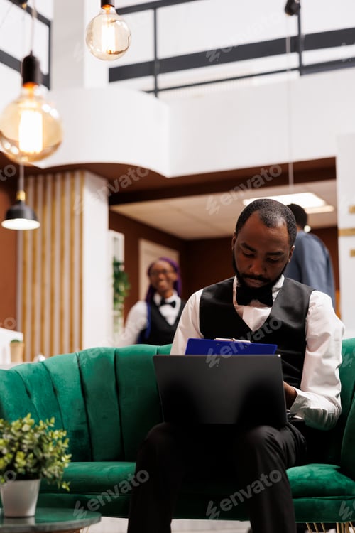 Preview: Hotel concierge entering data on laptop