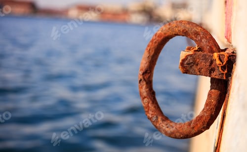 Preview: Rusty bollard waits at quay for a boat to be tied. Blur sea for background, closeup, details, banner