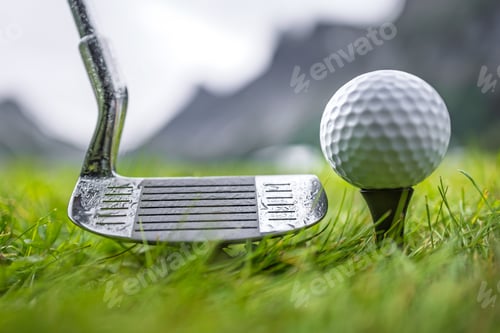 Preview: Golf club and ball on wet green field with mountains in background.