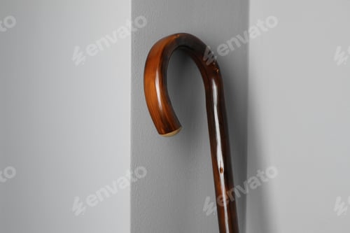 Preview: Elegant Curved Wooden Walking Cane Against Gray Wall