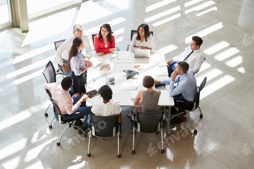 Preview: Businesswoman addressing colleagues at table, elevated view