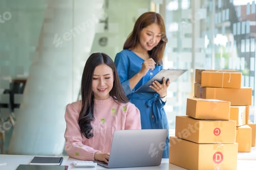 Preview: Two beautiful young Asian business owner woman prepare parcel box and check online orders