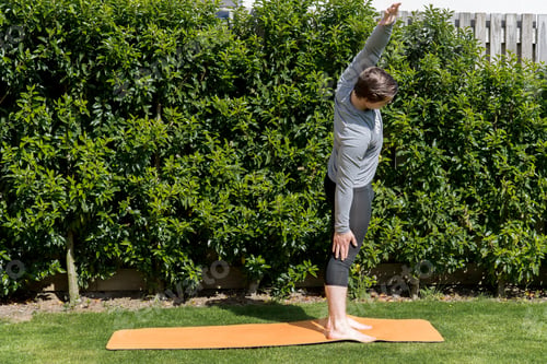 Preview: Young fit male practicing yoga and stretching outdoors