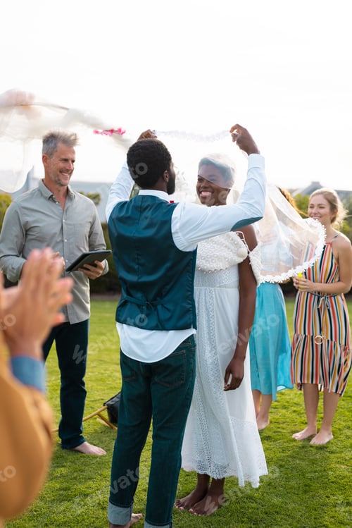 Preview: Happy african american couple holding veil and smiling during wedding