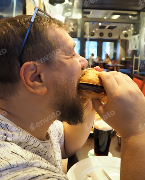 Preview: A man bites off a big Burger in a cafe