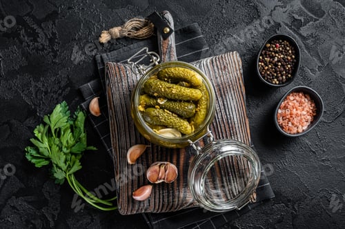 Preview: Pickled Gherkin cucumbers with dill, garlic and spices in glass jar. Black background. Top view