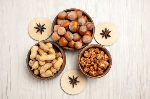 Preview: top view different nuts inside little pots on white desk snack walnut hazelnut nut