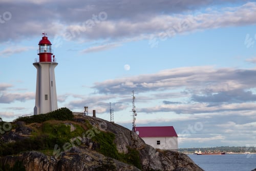 Preview: Lighthouse on a rocky shore during a vibrant cloudy sunset