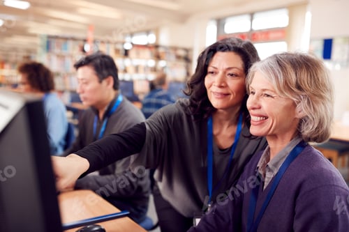 Preview: Teacher With Group Of Mature Adult Students In Class Working At Computers In College Library