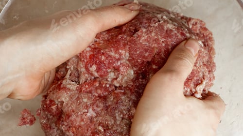 Preview: Closeup of female hands mixing and beating minced beef meat