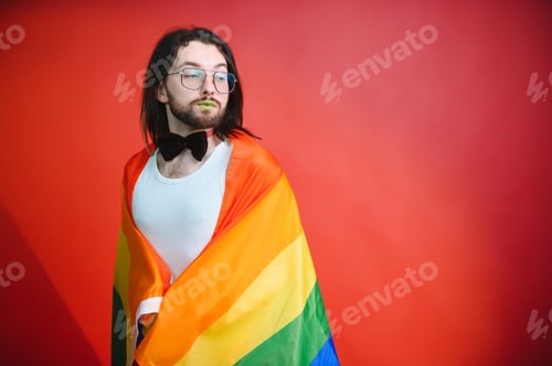 Preview: Gay man hold rainbow striped flag isolated on colored background studio portrait.