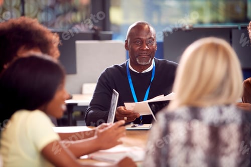 Preview: University Or College Students Sitting Around Table With Tutor Collaborating In Seminar On Laptop