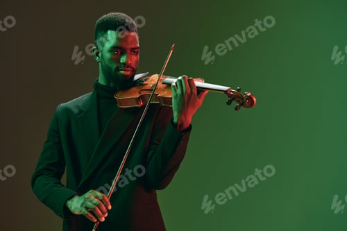 Preview: Talented African American man in suit playing the violin against a vibrant green background