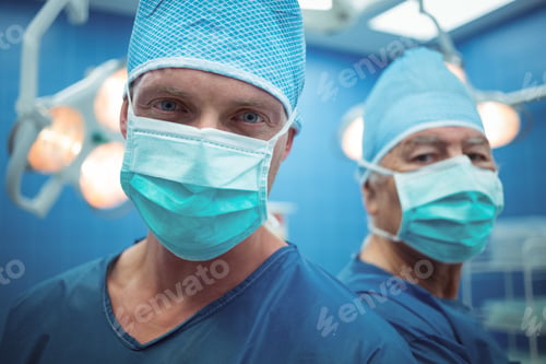 Preview: Portrait of male surgeons wearing surgical mask in operation theater