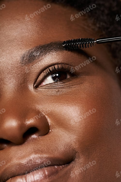 Preview: Stunning young African American woman enhancing her natural beauty in a studio