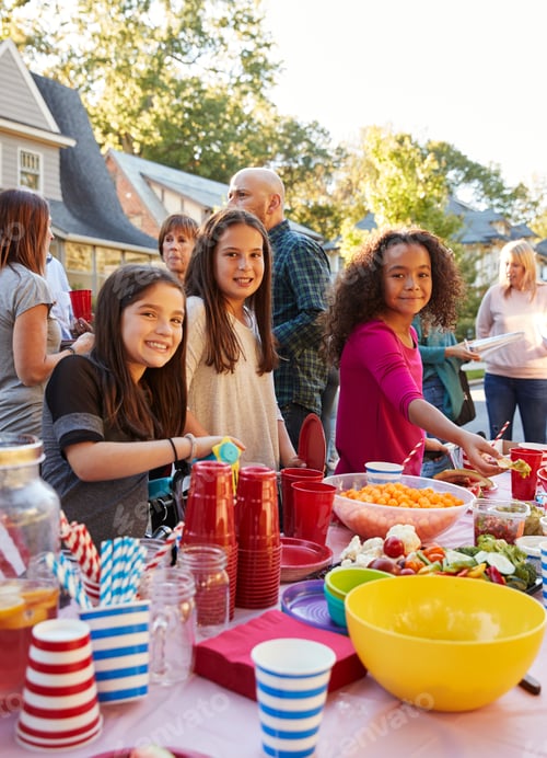 Preview: Pre-teen girls smiling to camera at a block party food table