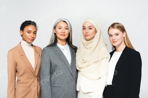 Preview: beautiful multicultural businesswomen looking at camera isolated on white