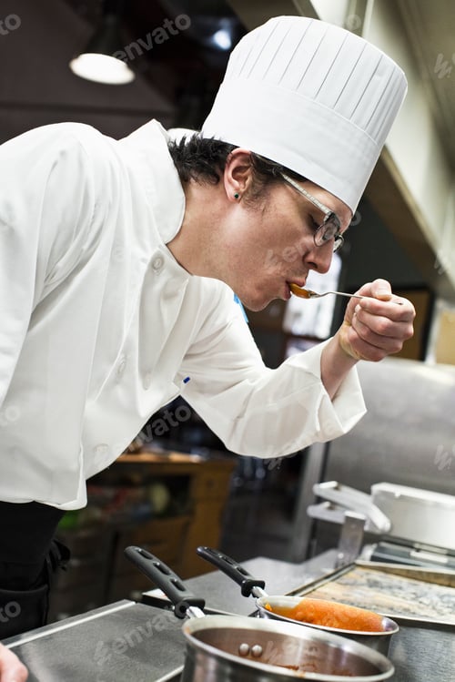 Preview: A caucasian male chef tastes a sample of the sauce he is making in a commercial kitchen,