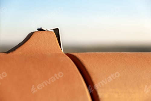Preview: Closeup of yellow ceramic roofing ridge tiles on top of residential building roof under construction