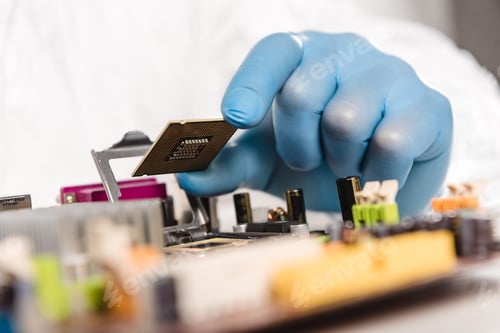 Preview: cropped view of microchip in hand of male scientist near motherboard