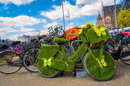 Preview: Closeup shot of a decorative grass bicycle parked close to other bikes in a street in Amsterdam