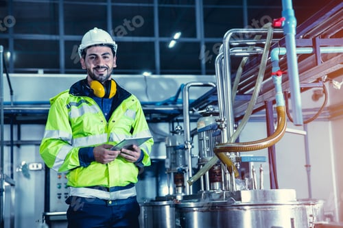Preview: Happy engineer male worker working in factory using tablet computer to check boiler water pipe
