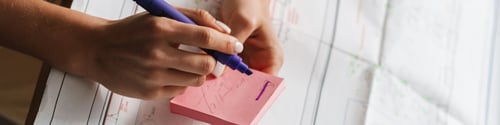 Preview: Young brunette woman working with drawings while sitting at desk working with drawings