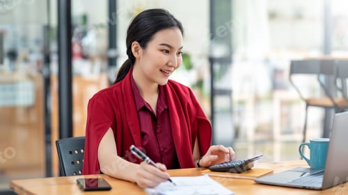 Preview: Charming young Asian businesswoman wearing red dress working at the office.