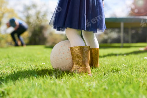Preview: Low section of girl wearing sparkly wellington boots playing with ball