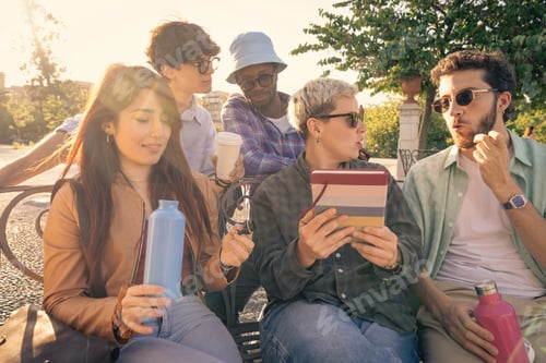Preview: Diverse group of students collaborating with a laptop outdoors on a park bench.