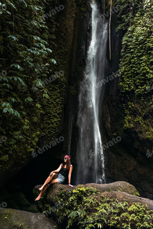 Preview: Beautiful girl at a waterfall on the island of Bali Indonesia, vertical view