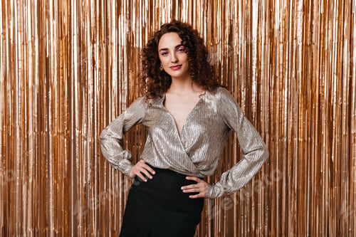 Preview: Portrait of woman in silver blouse posing on shiny background
