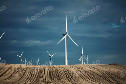 Preview: A number of wind turbines reaching into the distance in the farming landscape. Fields of stubble.