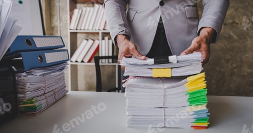 Preview: work from office A businessman works a bunch of paper files to find information on his desk at home.