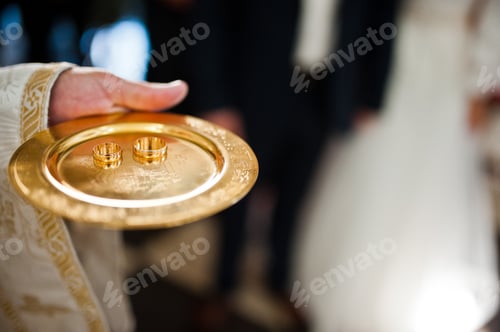 Preview: wedding rings on discus at hand of priest